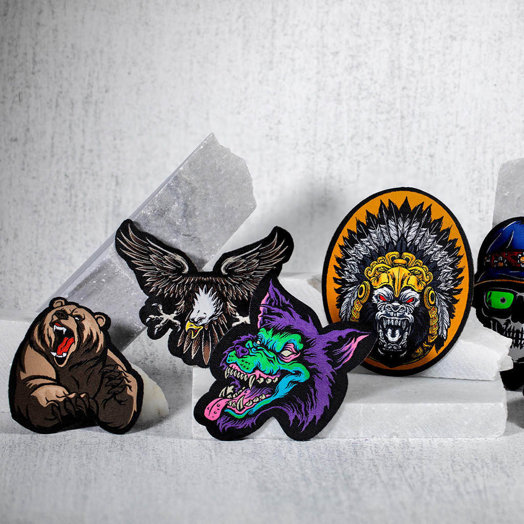 Colección de varios parches bordados con formas de animales y calaveras sobre fondo claro.
