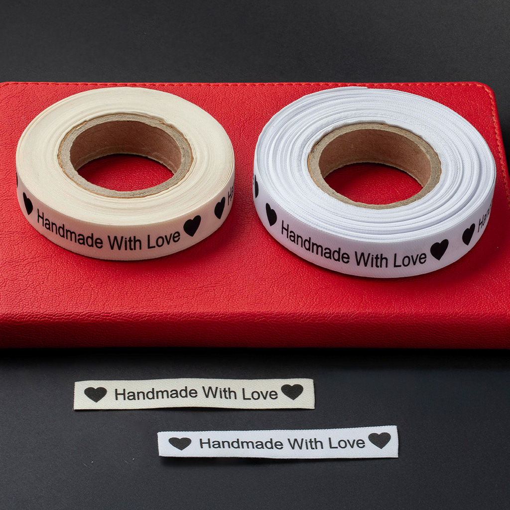 Dos rollos de cinta textil blanca impresos con corazones negros y texto.