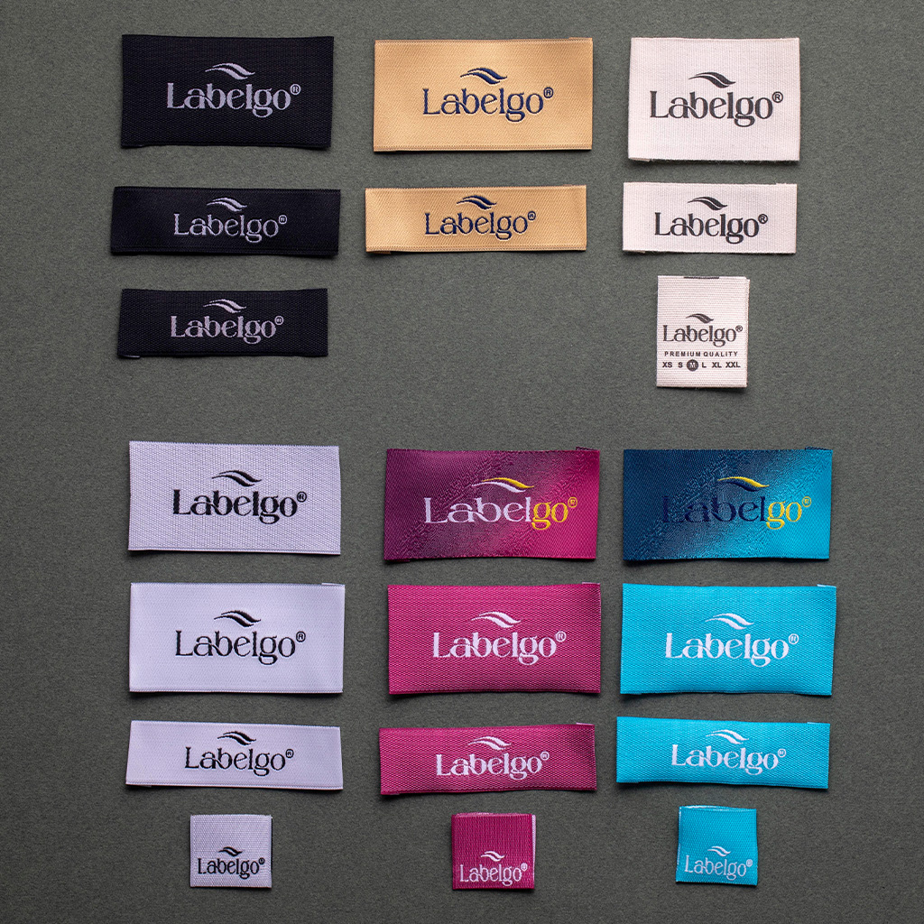 Muestrario de etiquetas de ropa rectangulares en una amplia gama de colores sobre fondo gris.
