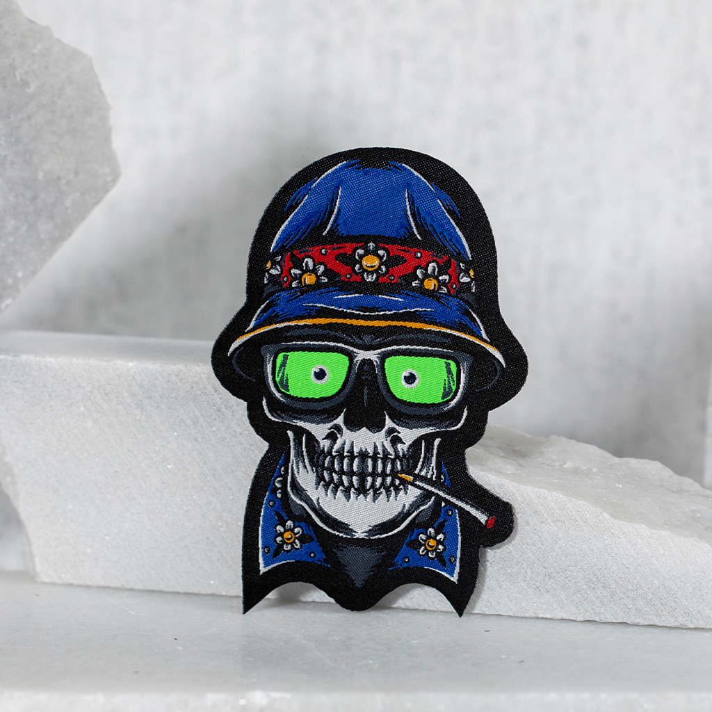 Parche bordado de calavera urbana con sombrero azul y gafas.